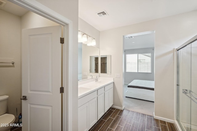 ensuite bathroom with toilet, visible vents, a shower stall, wood tiled floor, and ensuite bath