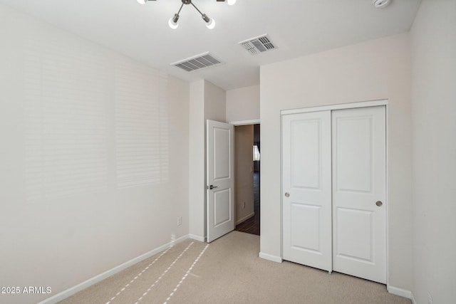 unfurnished bedroom featuring baseboards, a closet, visible vents, and light colored carpet