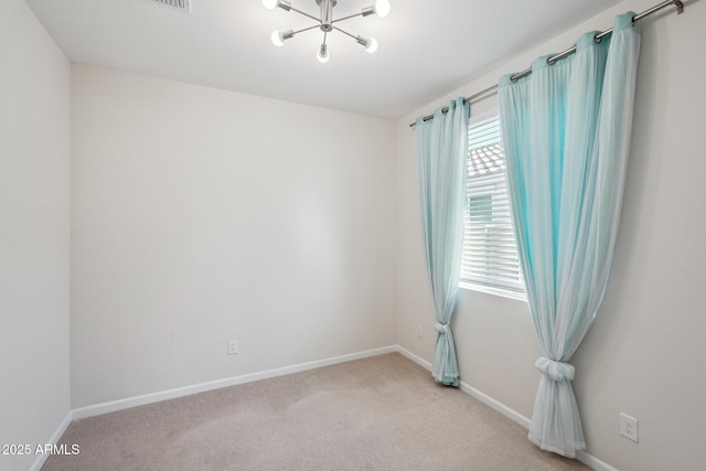 carpeted empty room featuring a notable chandelier