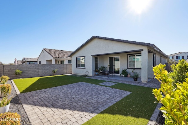 back of house with a patio area, a fenced backyard, a lawn, and stucco siding