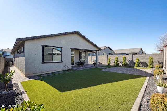 rear view of house with a yard, a patio area, a fenced backyard, and stucco siding