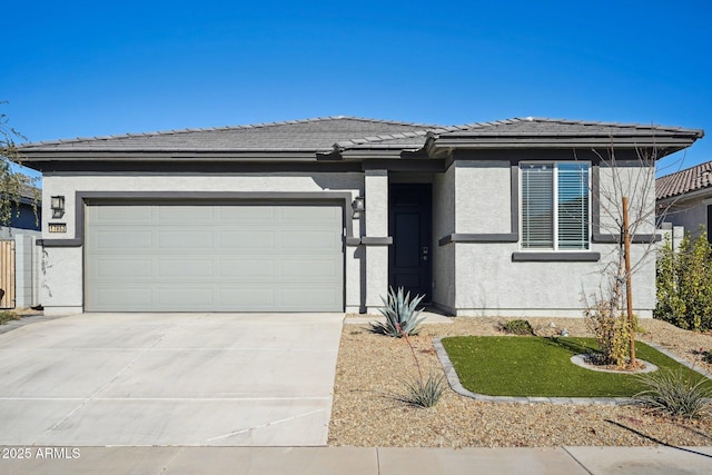 prairie-style house featuring concrete driveway, an attached garage, a tile roof, and stucco siding