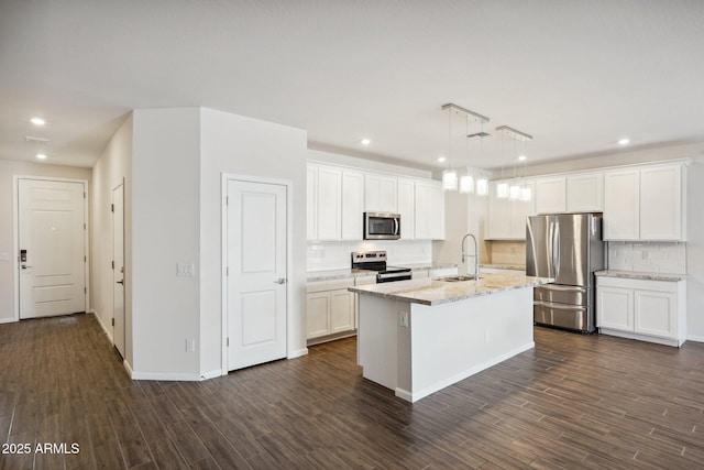 kitchen with sink, appliances with stainless steel finishes, a kitchen island with sink, white cabinets, and decorative light fixtures