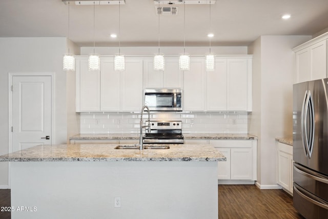 kitchen with appliances with stainless steel finishes, a kitchen island with sink, and pendant lighting