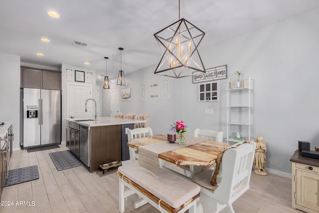 dining space with light hardwood / wood-style floors, a notable chandelier, and sink