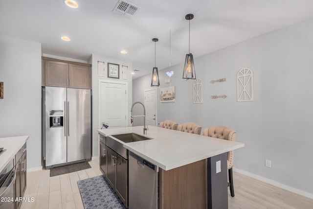 kitchen featuring light hardwood / wood-style flooring, appliances with stainless steel finishes, sink, and a kitchen island with sink