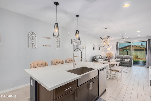 kitchen featuring dark brown cabinets, a kitchen island with sink, stainless steel dishwasher, pendant lighting, and sink