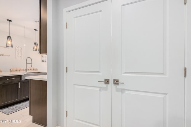 interior space featuring sink, dark brown cabinetry, decorative light fixtures, and light wood-type flooring