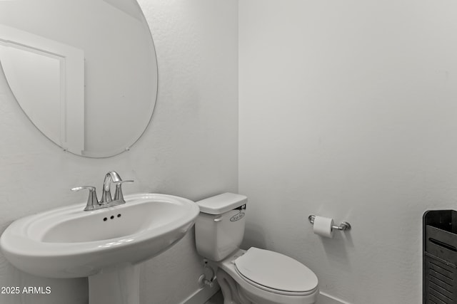 bathroom featuring toilet, baseboards, and a sink