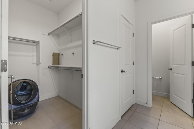 laundry room with laundry area, light tile patterned floors, baseboards, and washer / clothes dryer