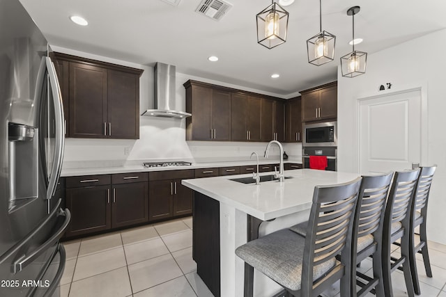 kitchen with oven, visible vents, stainless steel refrigerator with ice dispenser, a sink, and wall chimney range hood