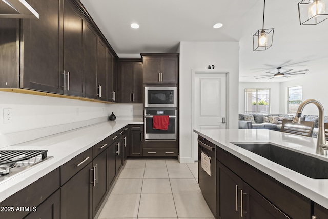 kitchen featuring a sink, stainless steel appliances, dark brown cabinetry, light countertops, and light tile patterned floors