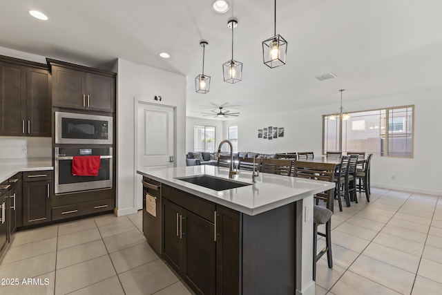 kitchen featuring light tile patterned flooring, built in microwave, a sink, light countertops, and stainless steel oven