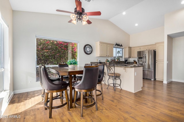 dining area with hardwood / wood-style flooring, high vaulted ceiling, and ceiling fan