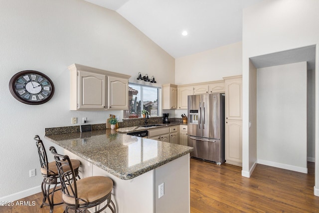 kitchen with sink, kitchen peninsula, dark stone counters, and stainless steel fridge with ice dispenser