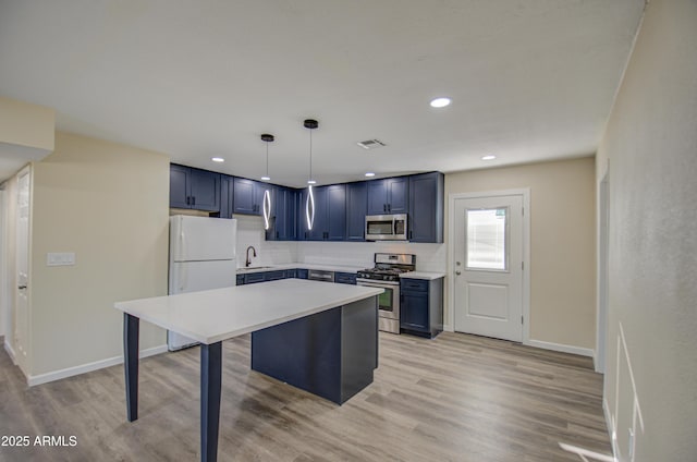 kitchen with hanging light fixtures, decorative backsplash, light wood-type flooring, a kitchen bar, and stainless steel appliances