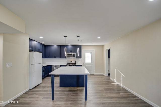 kitchen featuring blue cabinetry, hanging light fixtures, stainless steel appliances, a kitchen breakfast bar, and backsplash