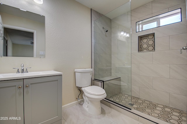 bathroom featuring a tile shower, tile patterned floors, vanity, and toilet