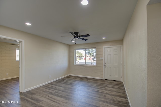 spare room with ceiling fan, dark wood-type flooring, and brick wall