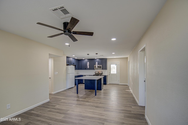 kitchen with a kitchen breakfast bar, light wood-type flooring, stainless steel appliances, blue cabinetry, and a center island