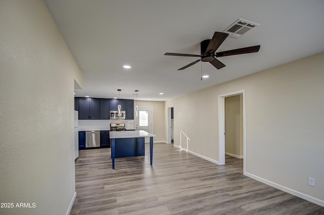 kitchen with hanging light fixtures, light hardwood / wood-style floors, a kitchen island, a breakfast bar area, and stainless steel appliances