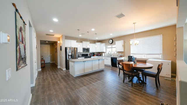 kitchen featuring decorative light fixtures, white cabinetry, a center island, and stainless steel appliances