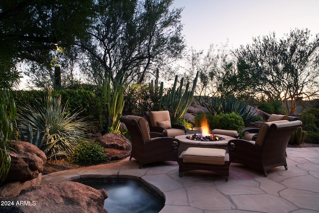 patio terrace at dusk featuring a hot tub and a fire pit