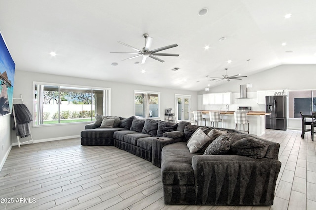 living room featuring baseboards, vaulted ceiling, a ceiling fan, and wood finish floors