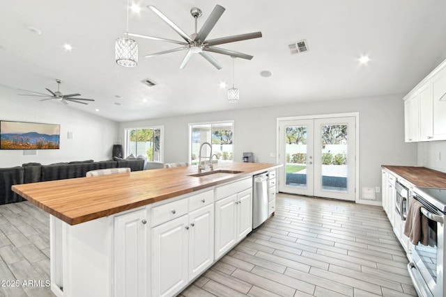 kitchen featuring a sink, ceiling fan, appliances with stainless steel finishes, vaulted ceiling, and butcher block countertops