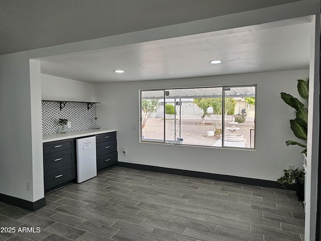 kitchen featuring baseboards, dark wood-style floors, white dishwasher, and light countertops