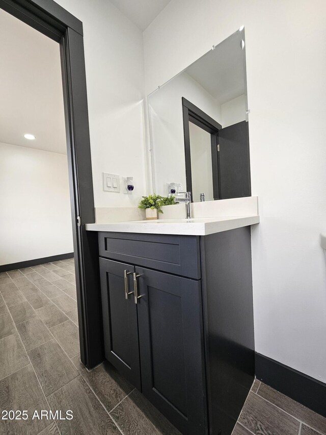 bathroom with wood finish floors, baseboards, and vanity