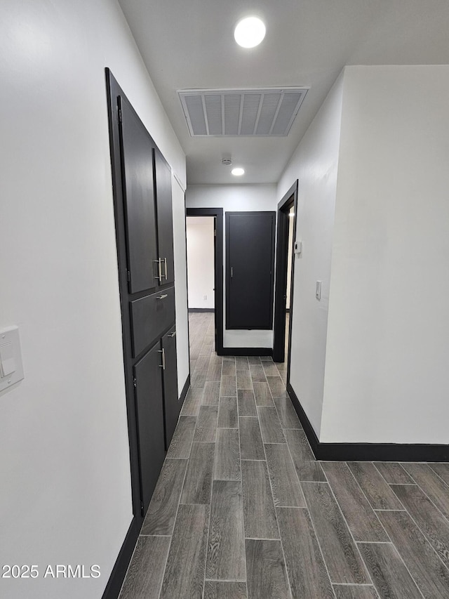 corridor with baseboards, visible vents, and wood finish floors