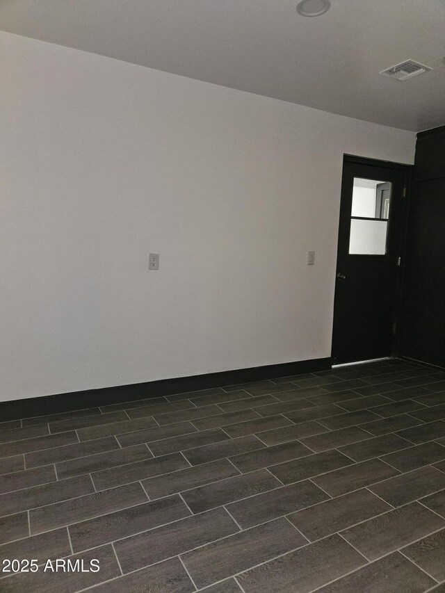 unfurnished room featuring visible vents, baseboards, and wood finish floors