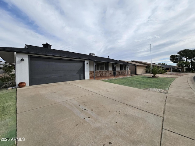 ranch-style home with brick siding, an attached garage, concrete driveway, and a front lawn