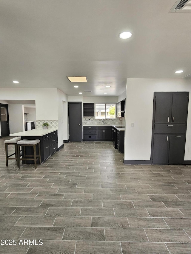 kitchen featuring tasteful backsplash, visible vents, dark cabinetry, and a sink