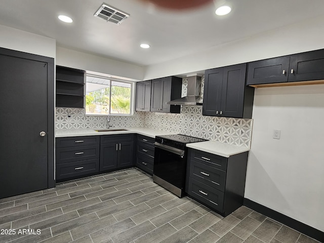 kitchen with visible vents, wall chimney range hood, decorative backsplash, electric range, and a sink