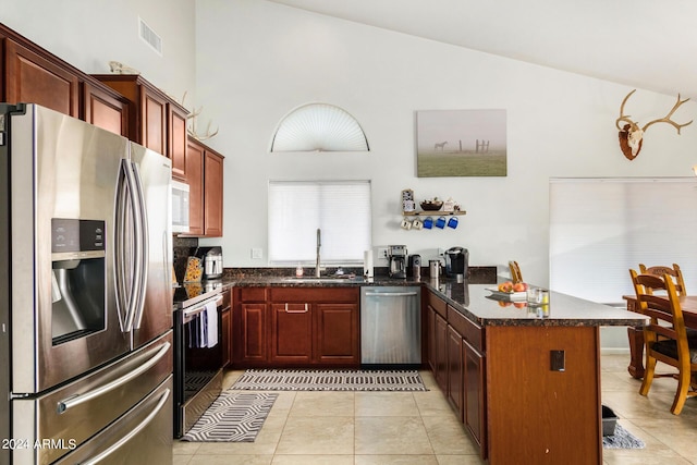 kitchen featuring visible vents, a sink, appliances with stainless steel finishes, a peninsula, and light tile patterned floors