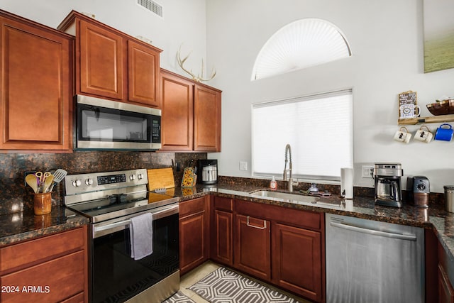 kitchen with dark stone countertops, sink, appliances with stainless steel finishes, and backsplash