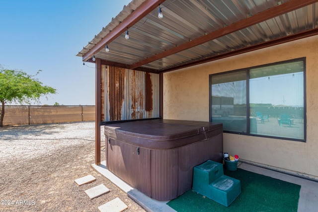 view of patio / terrace with a hot tub and fence