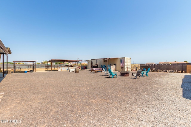 view of playground with an outdoor fire pit, an outdoor structure, and fence