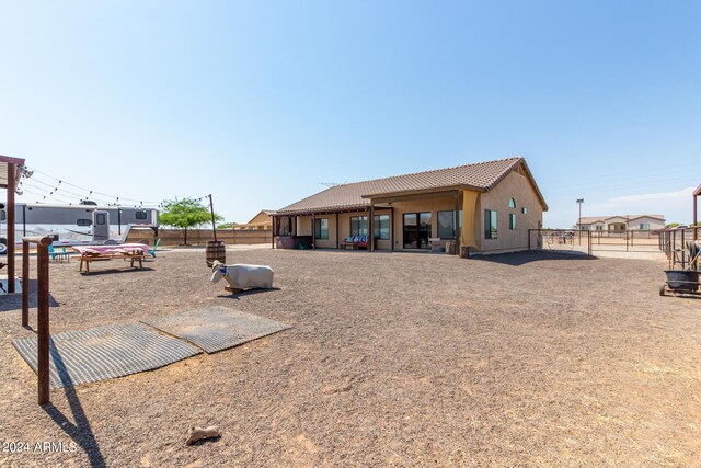 back of property featuring stucco siding, fence, and a tiled roof