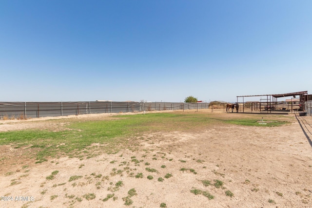 view of yard with an outdoor structure, an enclosed area, a rural view, and an exterior structure