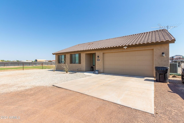 view of front facade featuring concrete driveway, a tiled roof, fence, and stucco siding