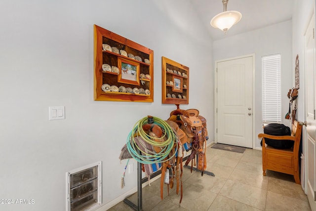 interior space with baseboards, light tile patterned flooring, and vaulted ceiling