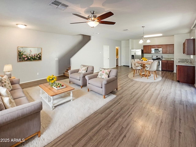 living room featuring ceiling fan with notable chandelier and hardwood / wood-style flooring