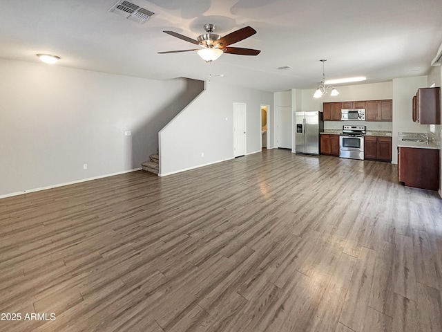 unfurnished living room with ceiling fan with notable chandelier and dark hardwood / wood-style floors