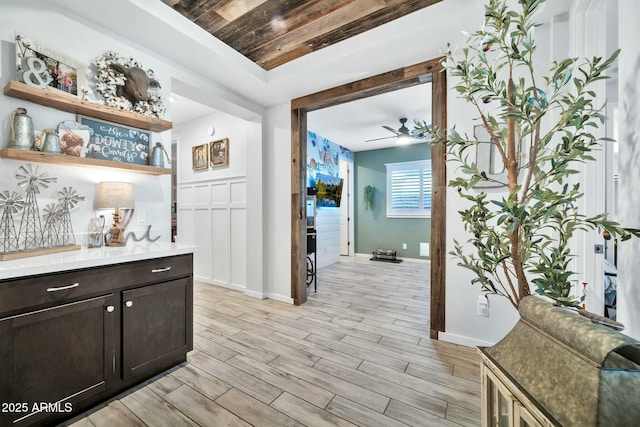 bar featuring ceiling fan, light hardwood / wood-style flooring, and dark brown cabinets