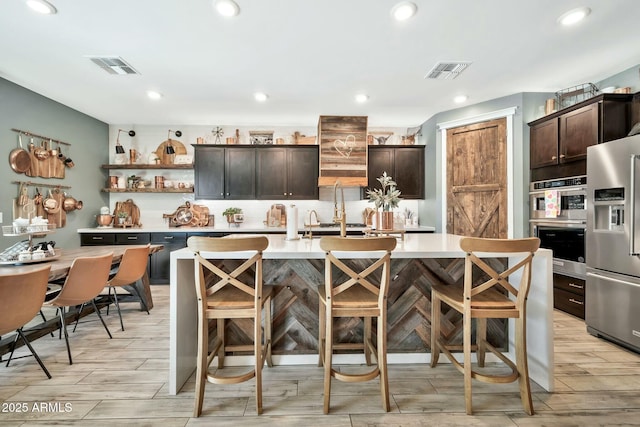 kitchen with stainless steel refrigerator with ice dispenser, a kitchen bar, and a center island with sink