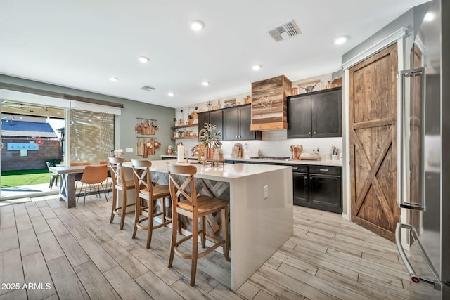 kitchen featuring appliances with stainless steel finishes, light hardwood / wood-style floors, a breakfast bar, and a kitchen island with sink