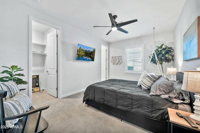 bedroom with a spacious closet, ceiling fan, and light colored carpet